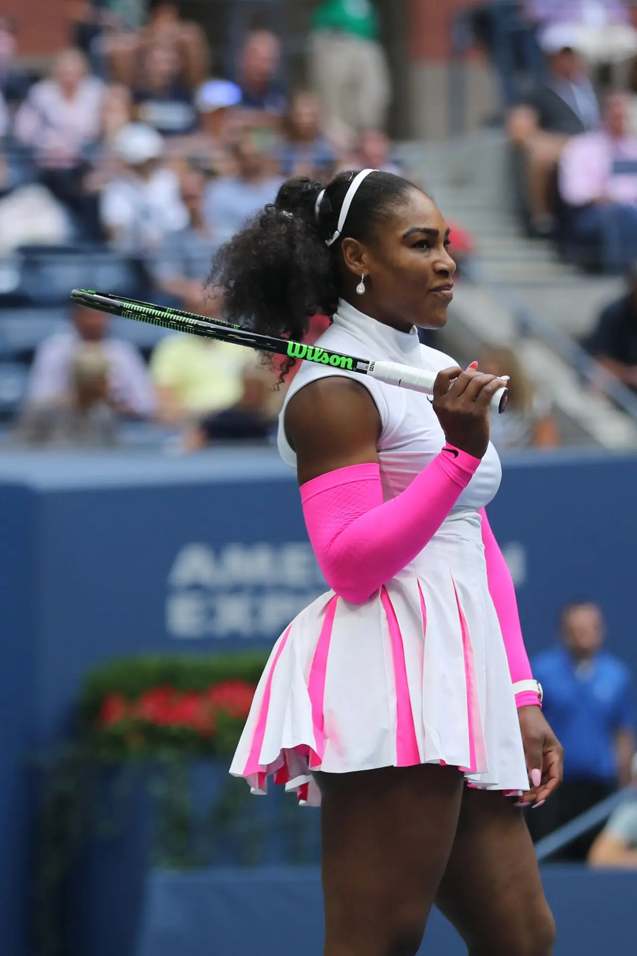 Serena Williams en pista con un conjunto de tenis blanco y rosa con mangas a juego
