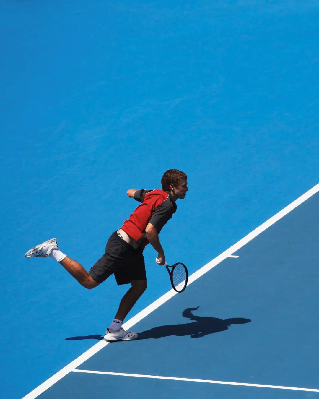 Joueur de tennis fonce au filet après un service puissant sur dur bleu