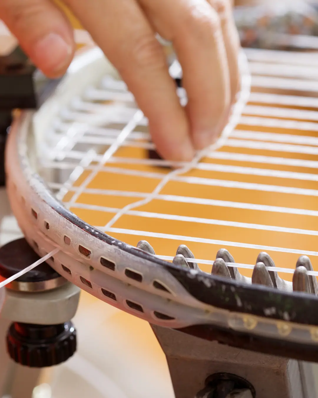 Dettaglio di una racchetta da tennis durante la nuova incordatura manuale, che mostra la precisione del processo.