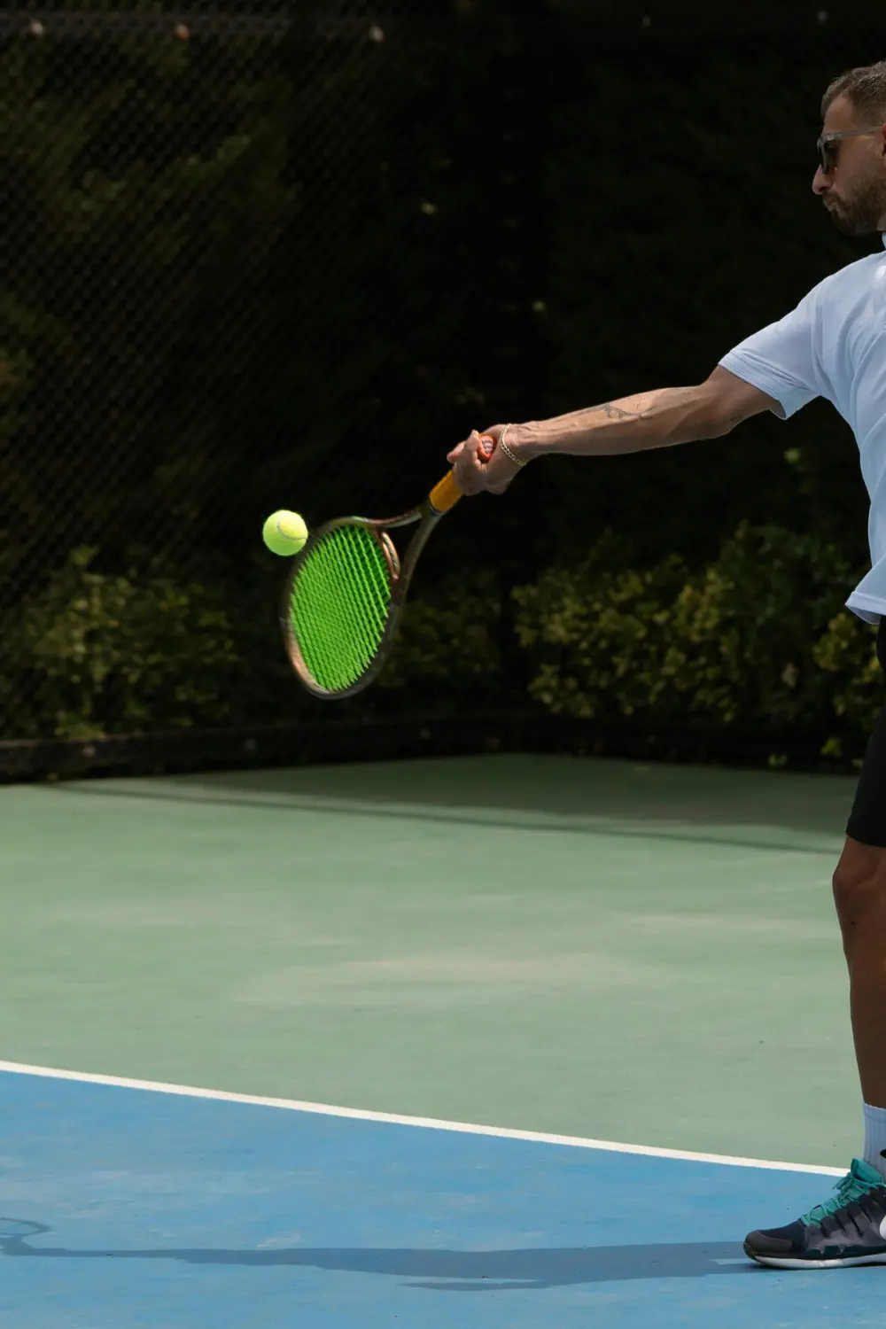 Gros plan sur une raquette de tennis qui se plie à l’impact lorsqu’elle frappe la balle sur un court en dur