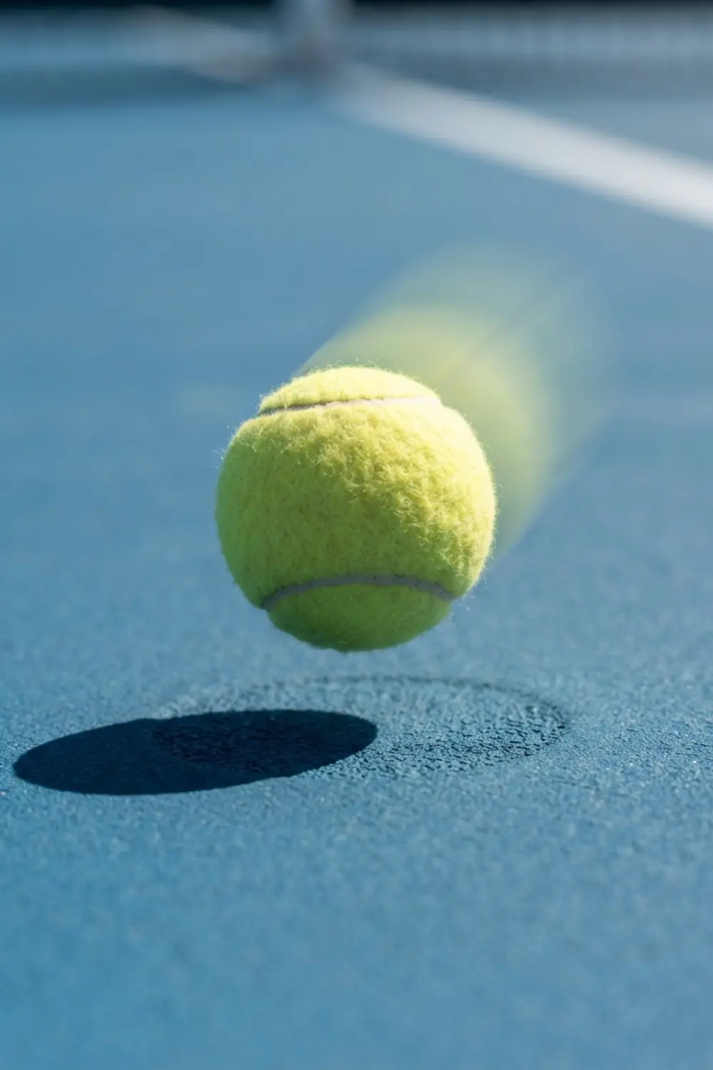 Le rebond de la balle sur un court en dur Balle de tennis juste après son rebond sur une surface acrylique bleue et texturée