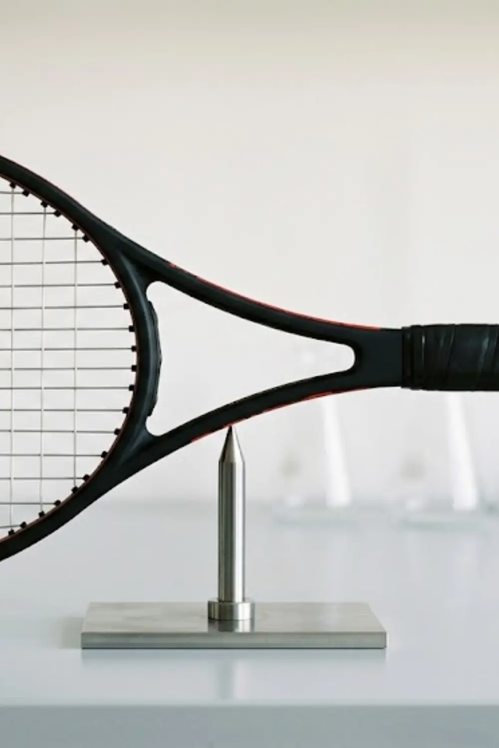 Adding Weight to the Throat or Handle Tennis racket balanced at the throat to illustrate racket balance and weight distribution